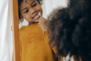 child brushing teeth in the mirror